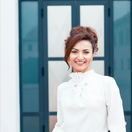 woman in white dress shirt and blue denim jeans smiling