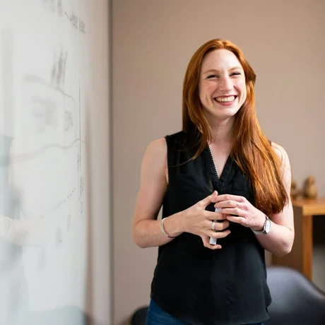 smiling woman presenting at whiteboard